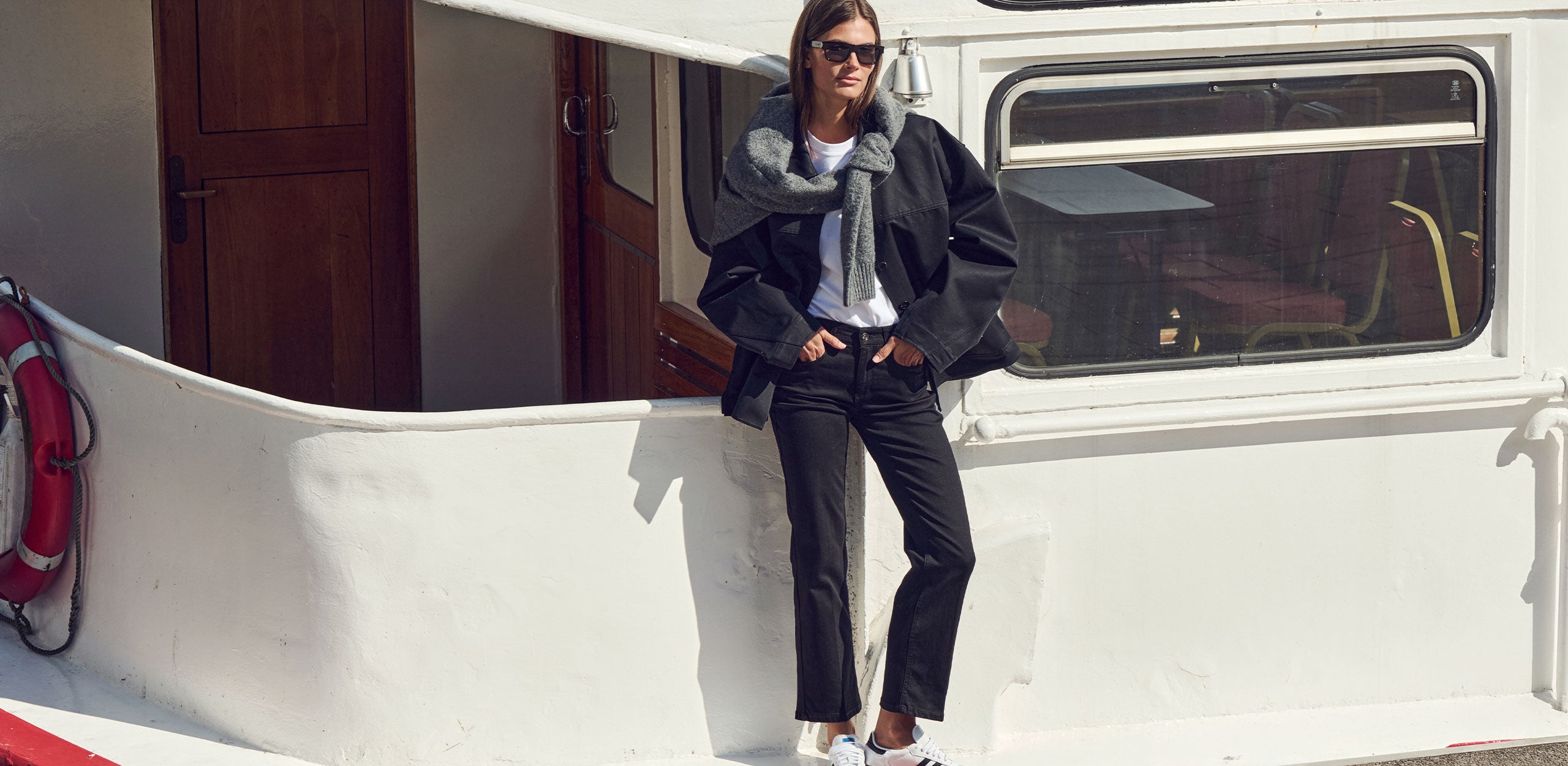 Woman in a black denim look with cropped jeans and jacket on board a ship.