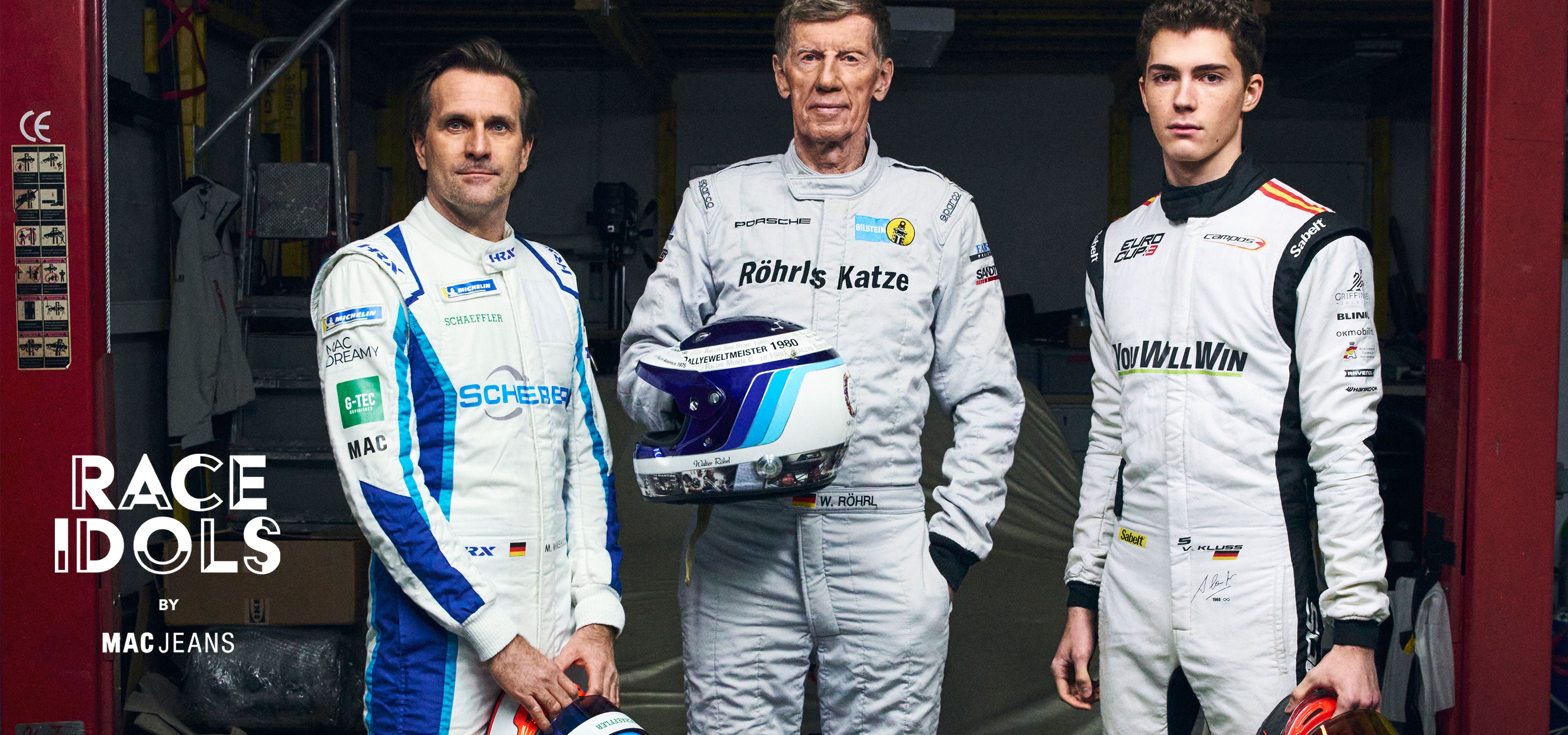 Three race drivers in professional racing suits stand side by side in a pit garage, representing different generations of motorsport. One holds a racing helmet, with the text “Race Idols by MAC Jeans” displayed.