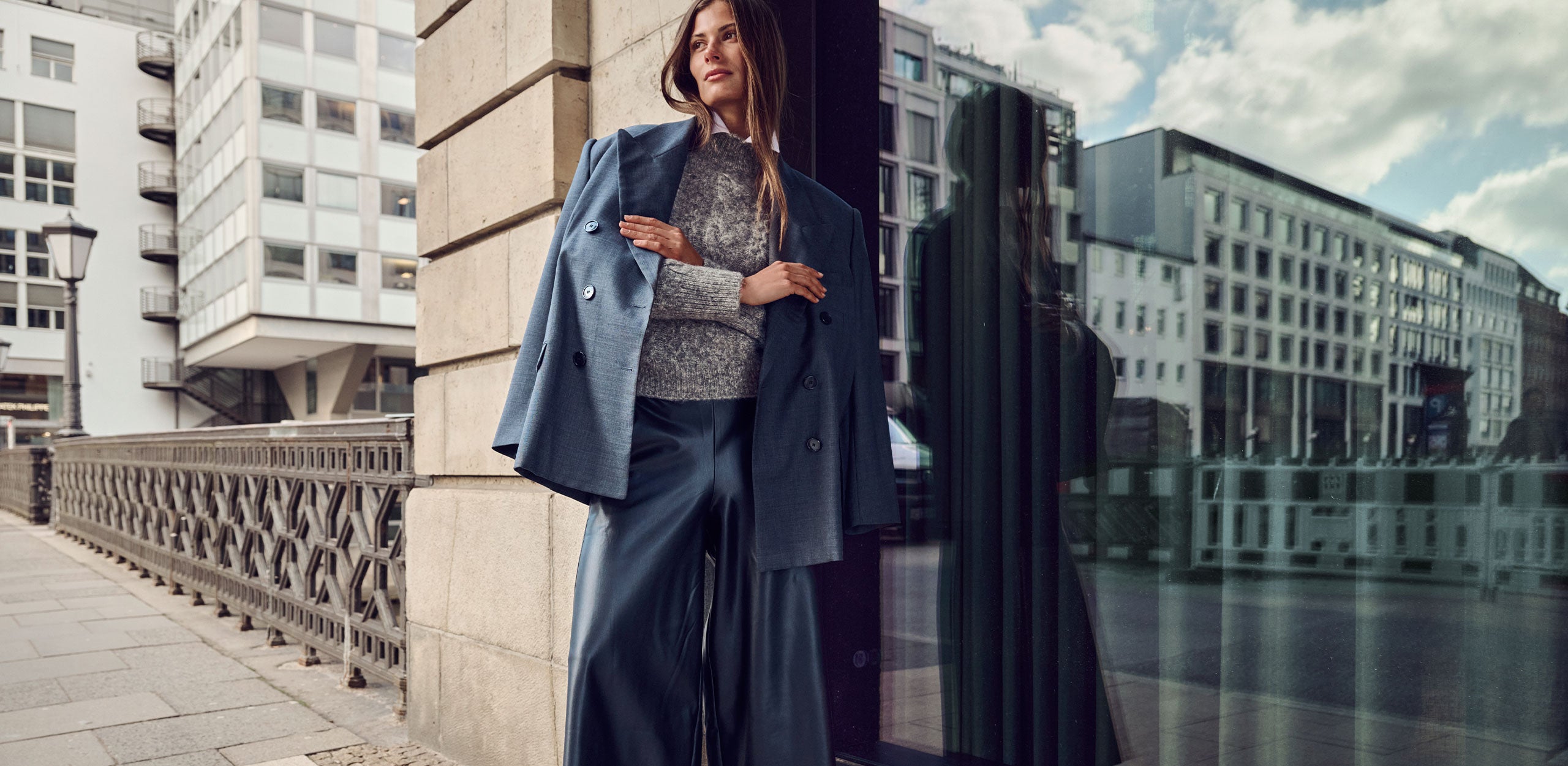Woman wearing a modern leather-look wide-leg pants outfit with a blue blazer in an urban setting.