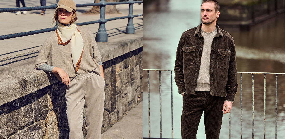 Woman wearing a beige corduroy outfit with a scarf and cap, and man wearing a dark brown corduroy jacket with matching pants.
