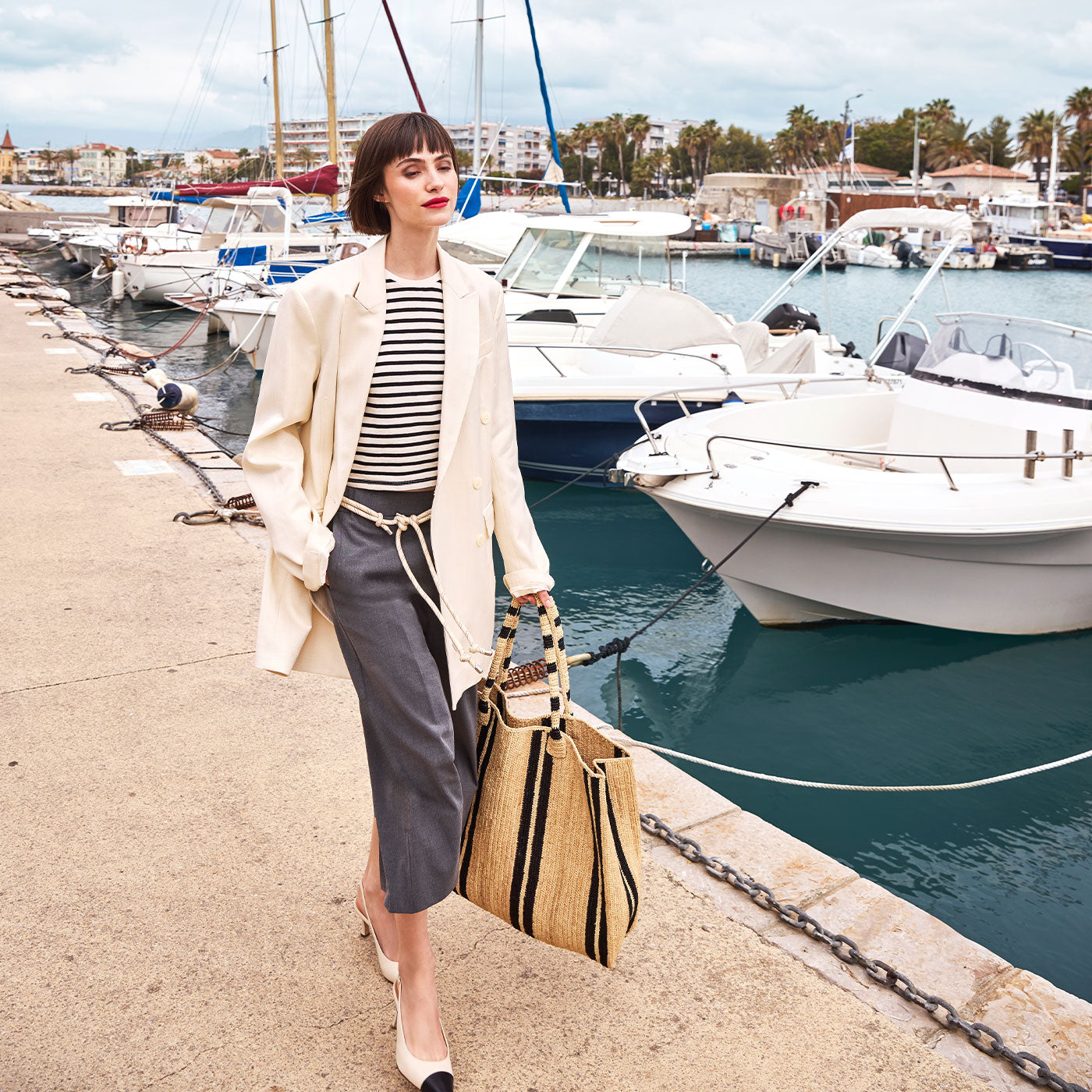 Woman strolling along a marina in a relaxed coastal look