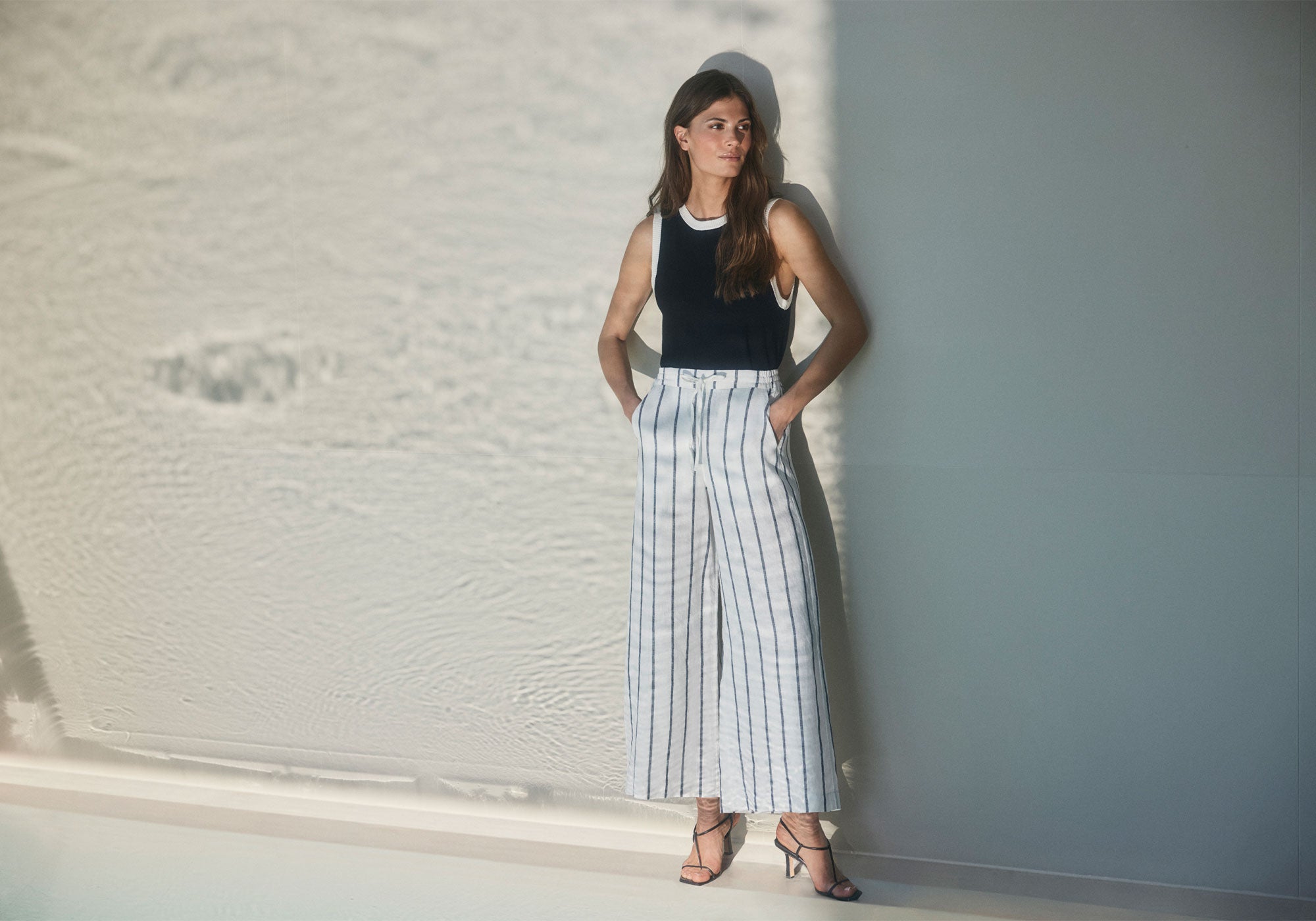 Wide striped linen trousers paired with a black top for a light summer look.